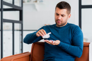 Man sitting on a couch examining medication in his hand