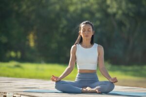 Woman practicing yoga in a lotus pose outdoors beside a calm lake