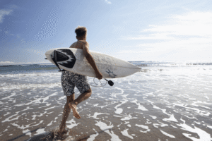 Young men surfing in the ocean, enjoying an active sober lifestyle