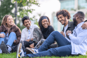 Diverse group of young adults laughing together outdoors on the grass
