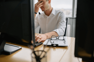 Exhausted man struggling to concentrate at his desk at work