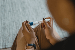 Woman holding a positive pregnancy test while weighing addiction treatment options